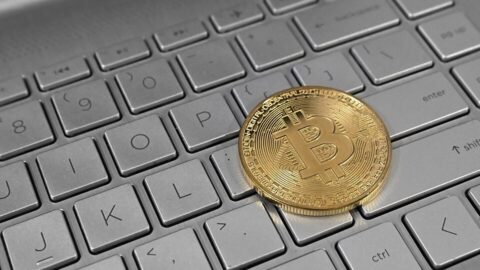 Gold physical bitcoin coin resting on a laptop keyboard