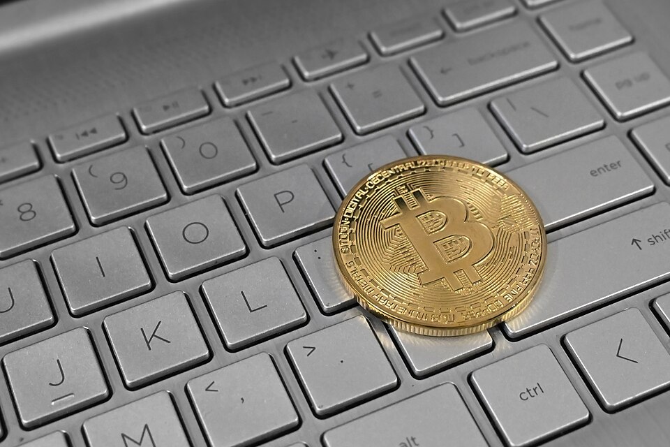 Gold physical bitcoin coin resting on a laptop keyboard