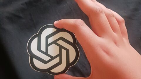 Hand holding an OpenAI logo sticker